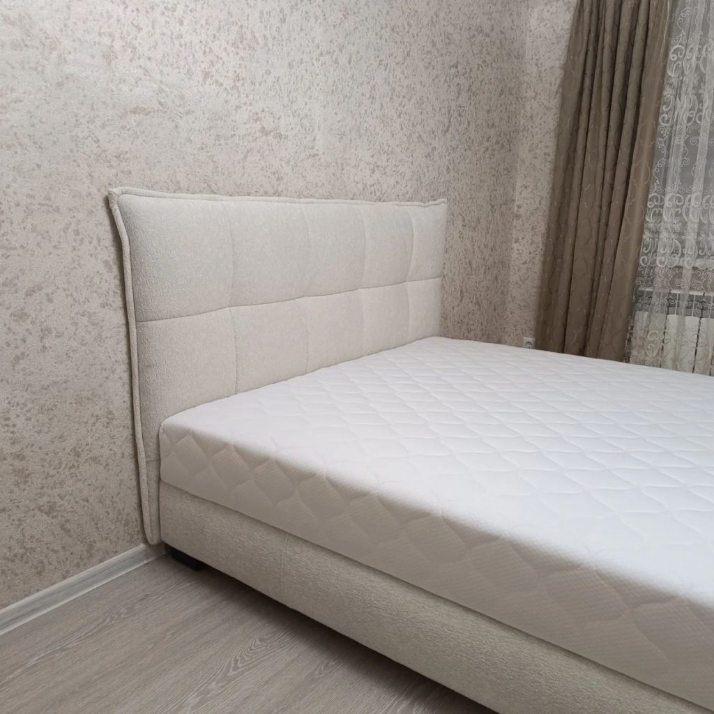 біле м’яке ліжко в сучасній спальні новобудови