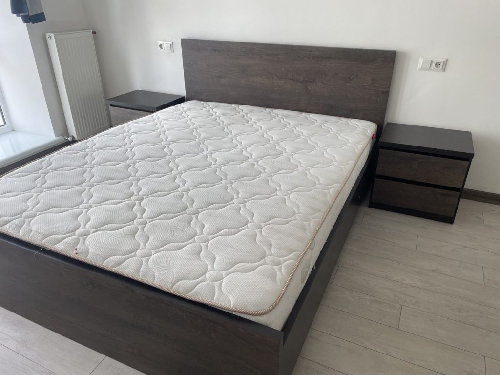 темне ліжко в спальні з світлими стінами