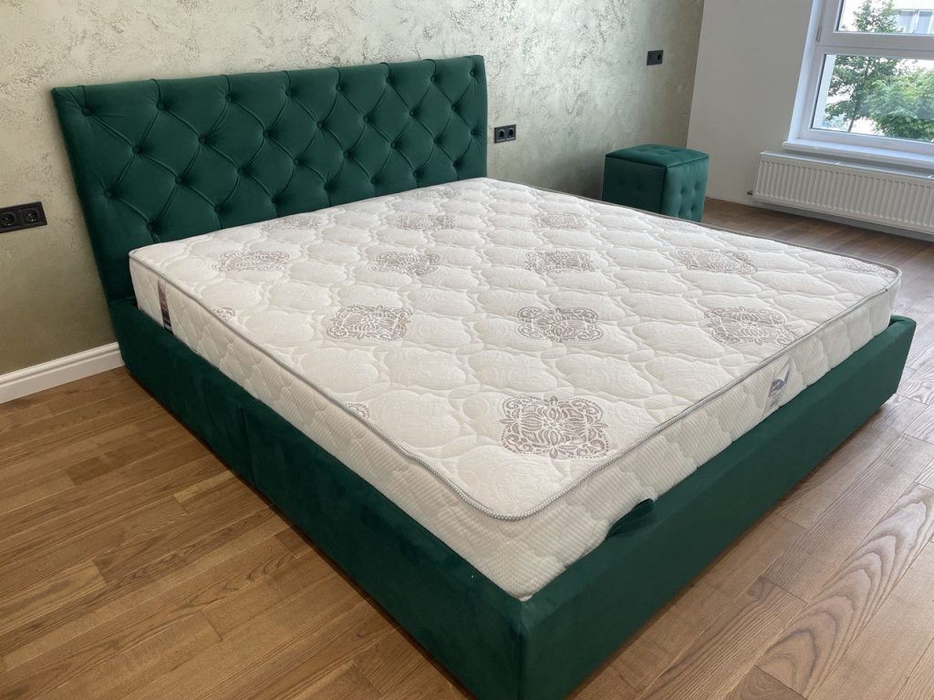 зелене м’яке ліжко з підйомним механізмом у спальні