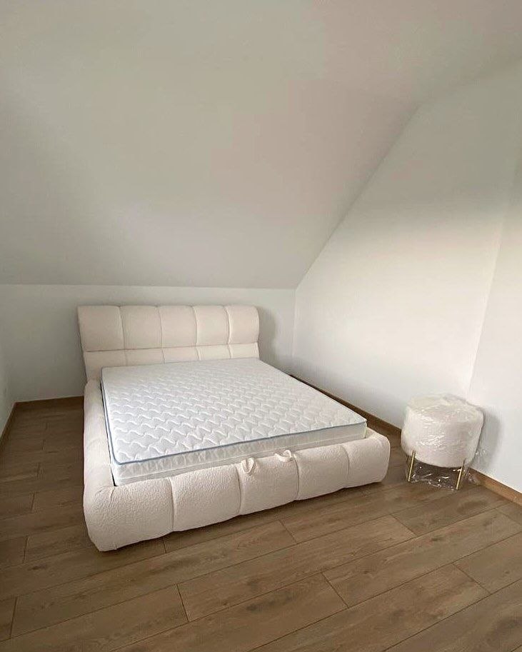 white bed with lift storage mechanism in attic bedroom